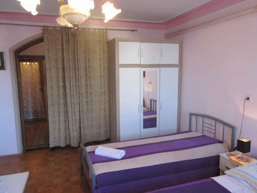 A bedroom with a bed, a wardrobe, a nightstand, and a lamp.