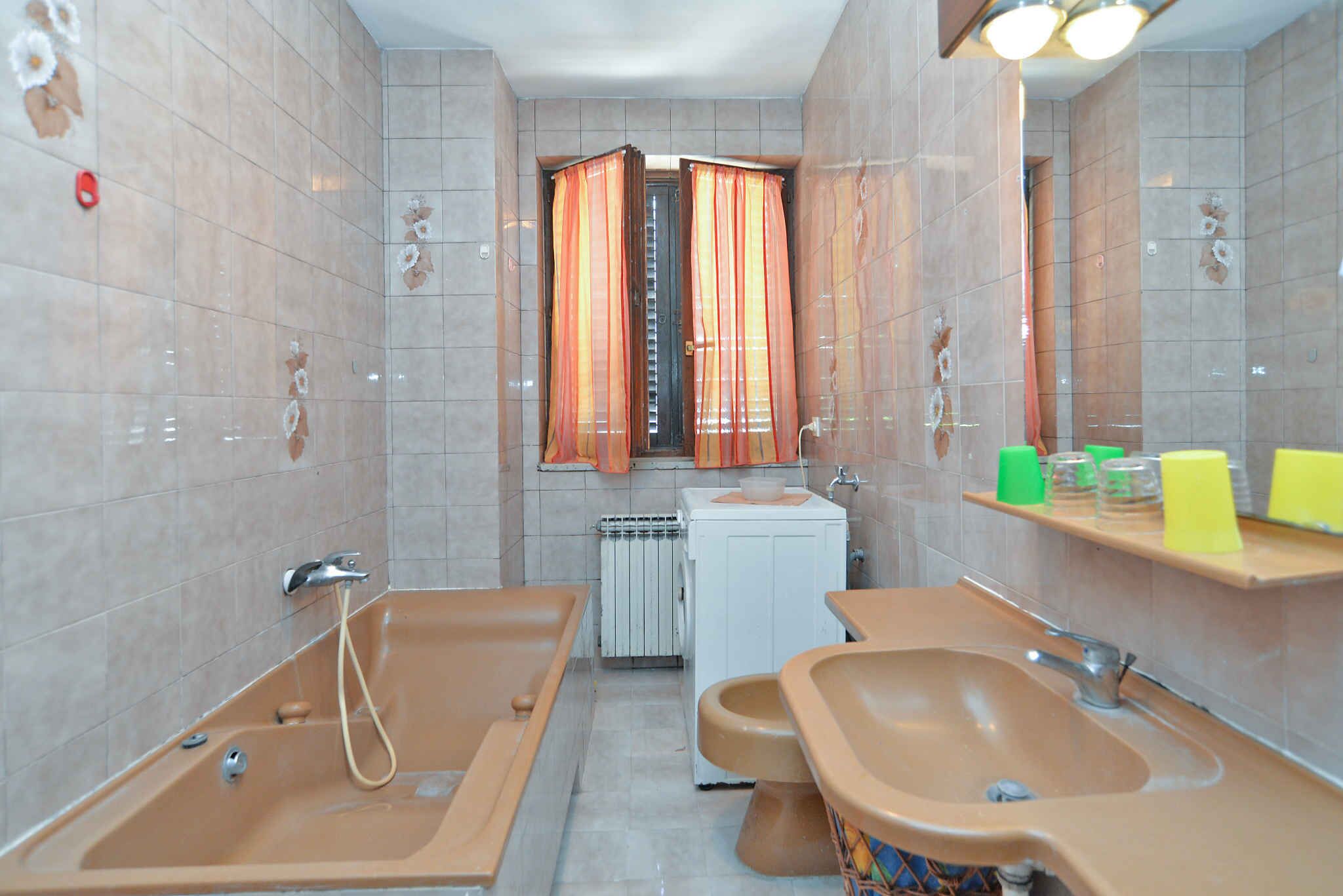 A bathroom with two sinks, a bathtub, a toilet, and a shower. There is a mirror above the sink and a window with curtains.