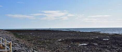 A rocky beach with a wooden walkway leading to the water.
