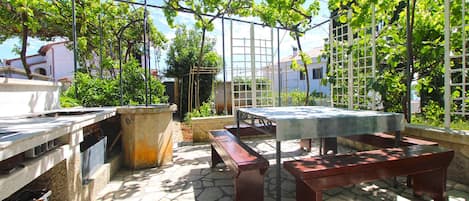 An outdoor patio with stone flooring, a wooden table, and a bench.