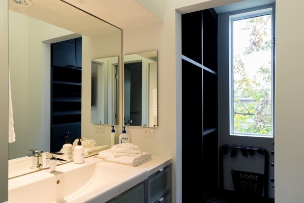 A modern bathroom with a large mirror, a sink, and a window.