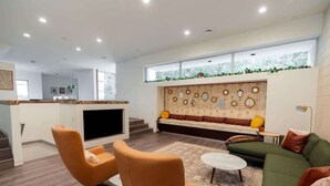 A modern living room with a sofa, armchairs, a coffee table, and a fireplace. - Rice Village Retreat - Rooftop deck & BBQ grill (Houston)