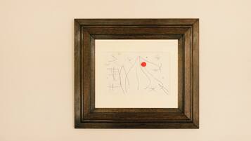 A framed abstract artwork on a white wall above a blue sofa.