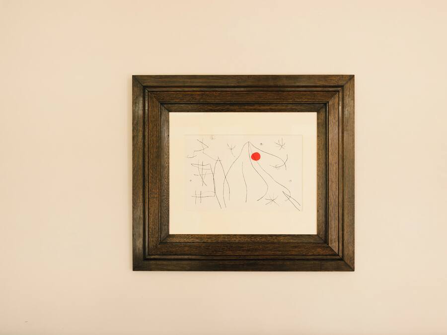 A framed abstract artwork on a white wall above a blue sofa.
