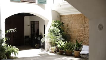 A courtyard with a pool, potted plants, and a white chair.