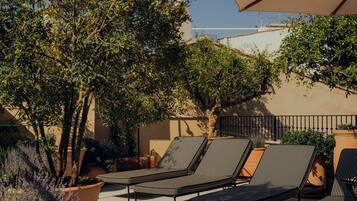 Un patio con sillones de descanso y una sombrilla grande.