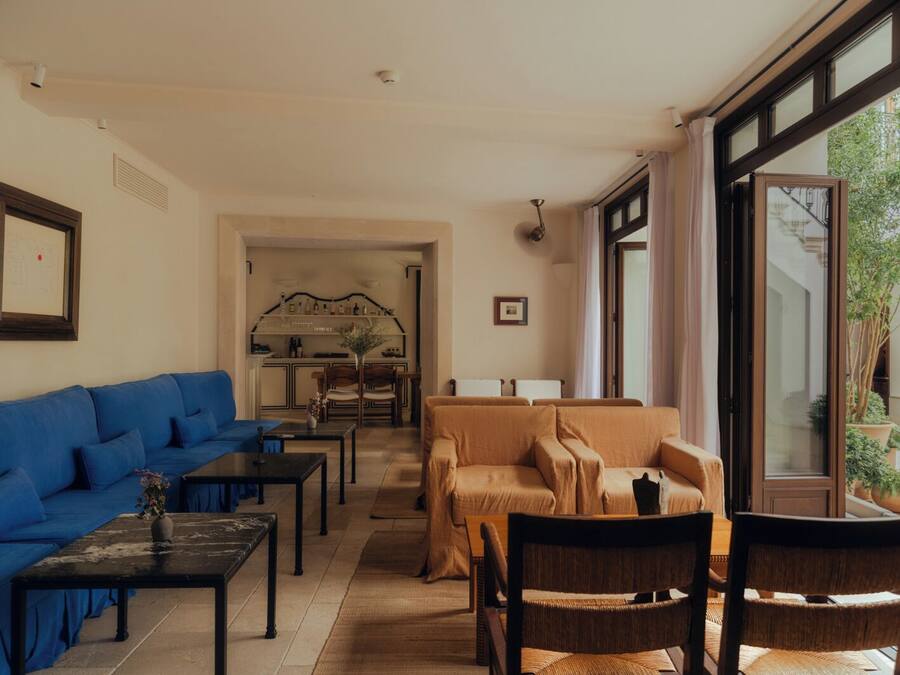 A modern living room with a blue sofa, a beige sofa, and a dining area with a kitchen in the background.