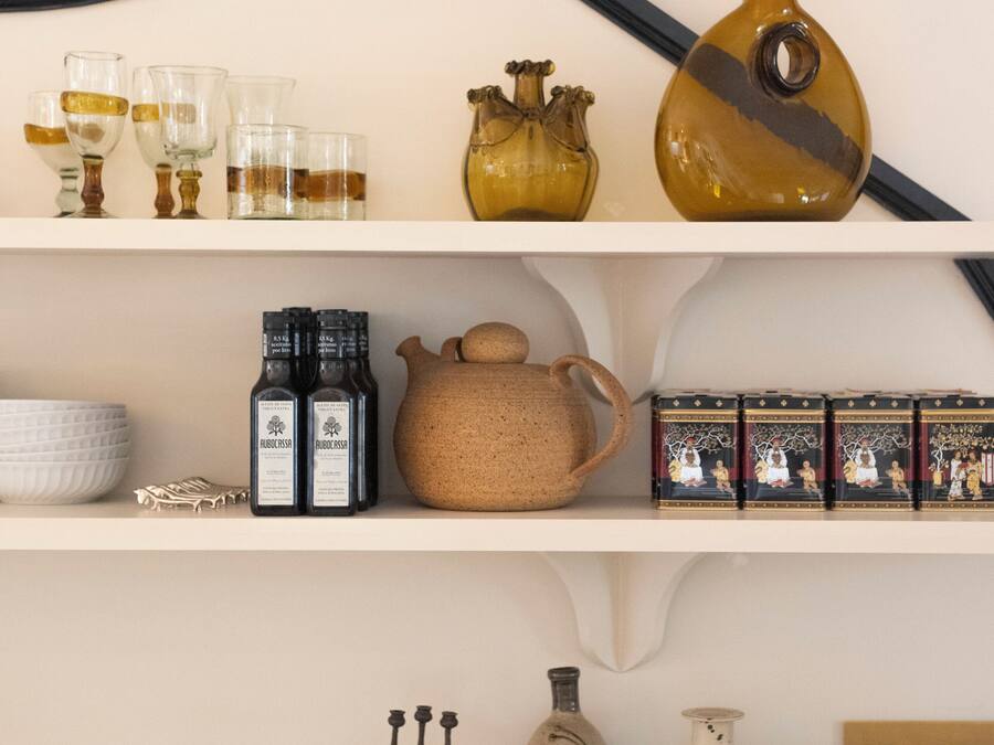 A shelf with various glassware, bottles, and decorative items.