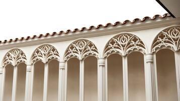 Fachada de edificio con arcos ornamentales de estilo gótico y tejado de tejas.