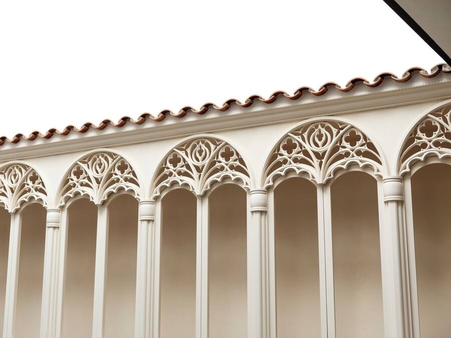 Fachada de edificio con arcos ornamentales de estilo gótico y tejado de tejas.