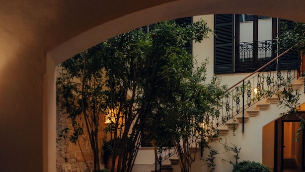 A courtyard with a central pool, surrounded by potted plants and a staircase leading to an upper level. - Portella Palma (Palma de Mallorca)