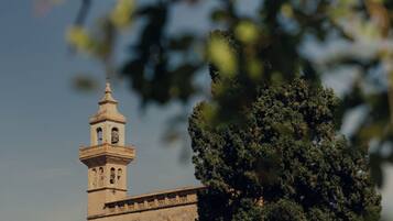 A historic building with a bell tower, surrounded by trees and foliage.