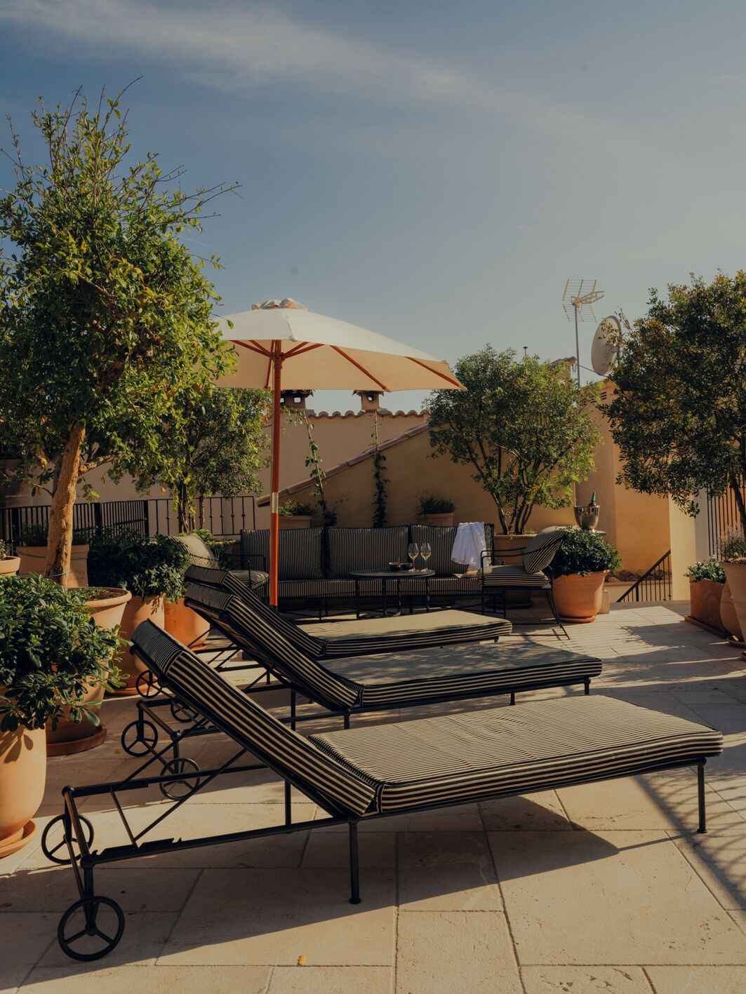 Une terrasse avec des fauteuils, une table et des plantes en pot.