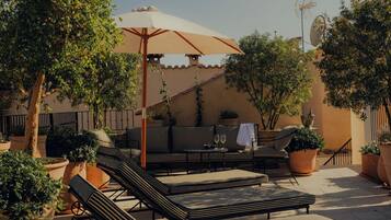 Une terrasse avec des fauteuils, une table et des plantes en pot.