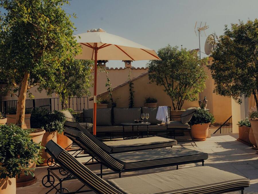 Un patio con sillones de descanso, una mesa y plantas en macetas.