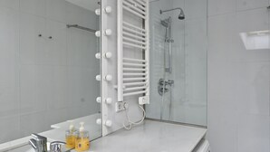 Un baño moderno con cabina de ducha de vidrio, tocador con espejo y perchero.