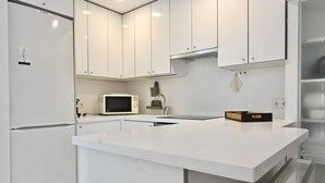 Una cocina moderna con armarios blancos, microondas y fregadero.