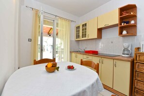 Enjoy meals in this cozy kitchen with a dining table for two, adjacent to a sliding glass door leading to an outdoor area.