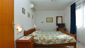 A bedroom with a wooden bed, bedside tables, a desk, a mirror, and a television.