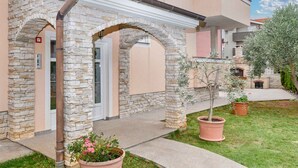 A building with stone arches, a door, and potted plants. - Holiday apartment with air conditioning (Medulin)
