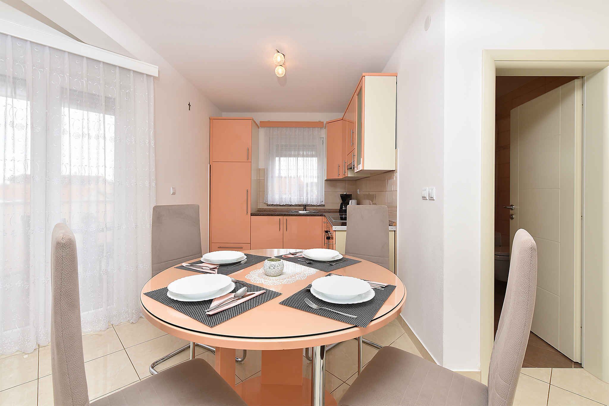 Una cucina compatta con elettrodomestici moderni e un'area pranzo con un tavolo rotondo apparecchiato per quattro persone.