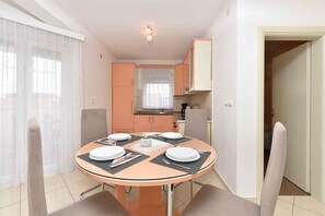 A compact kitchen with modern appliances and a dining area with a round table set for four. - Holiday apartment with air conditioning (Medulin)