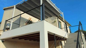 A modern building with a glass balcony and a staircase leading to an upper level.