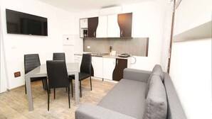 A modern kitchen with white cabinets, a built-in oven, and a flat-screen TV mounted above the counter.