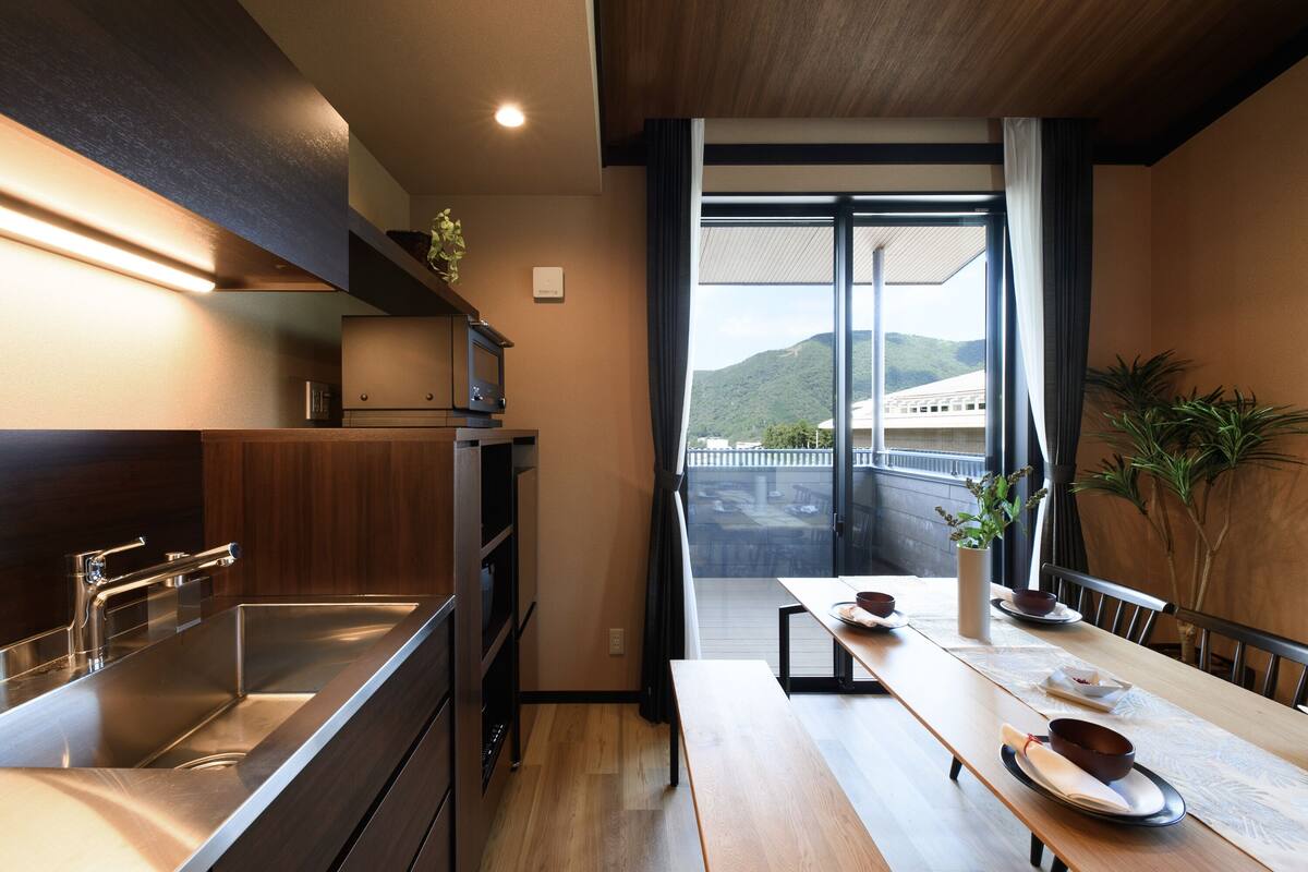 A modern kitchen with a built-in stove, a large sink, and a dining area with a wooden table and chairs.
