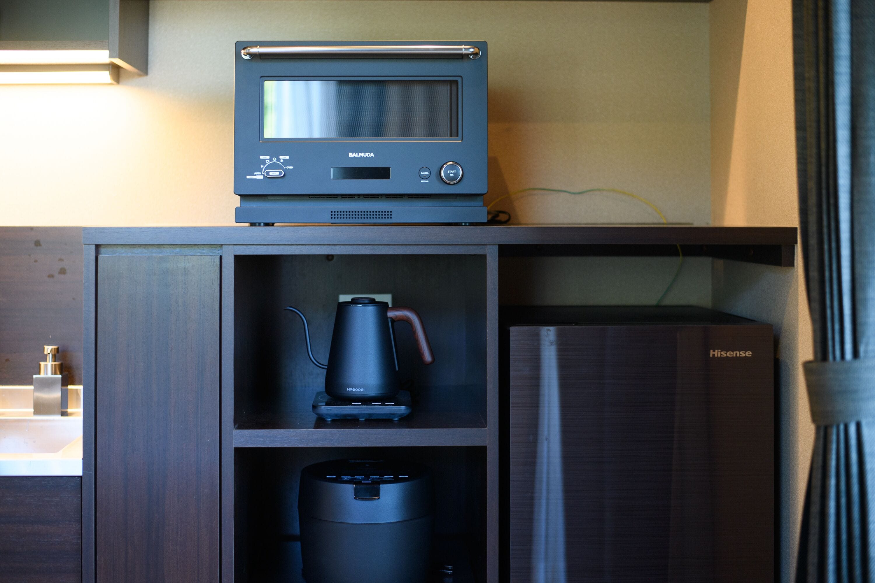 A kitchenette with a microwave, coffee maker, and a vacuum cleaner.