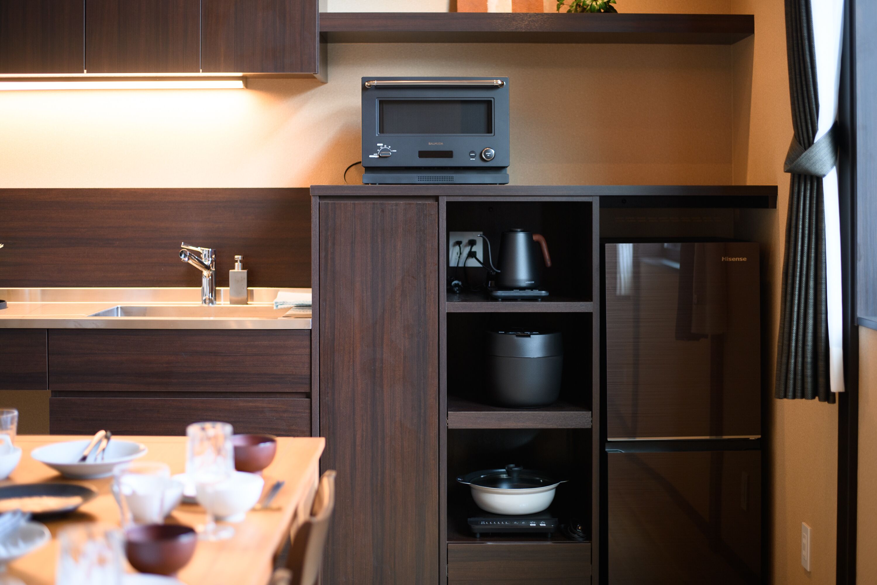 A modern kitchen with a built-in oven, a coffee maker, and a refrigerator.
