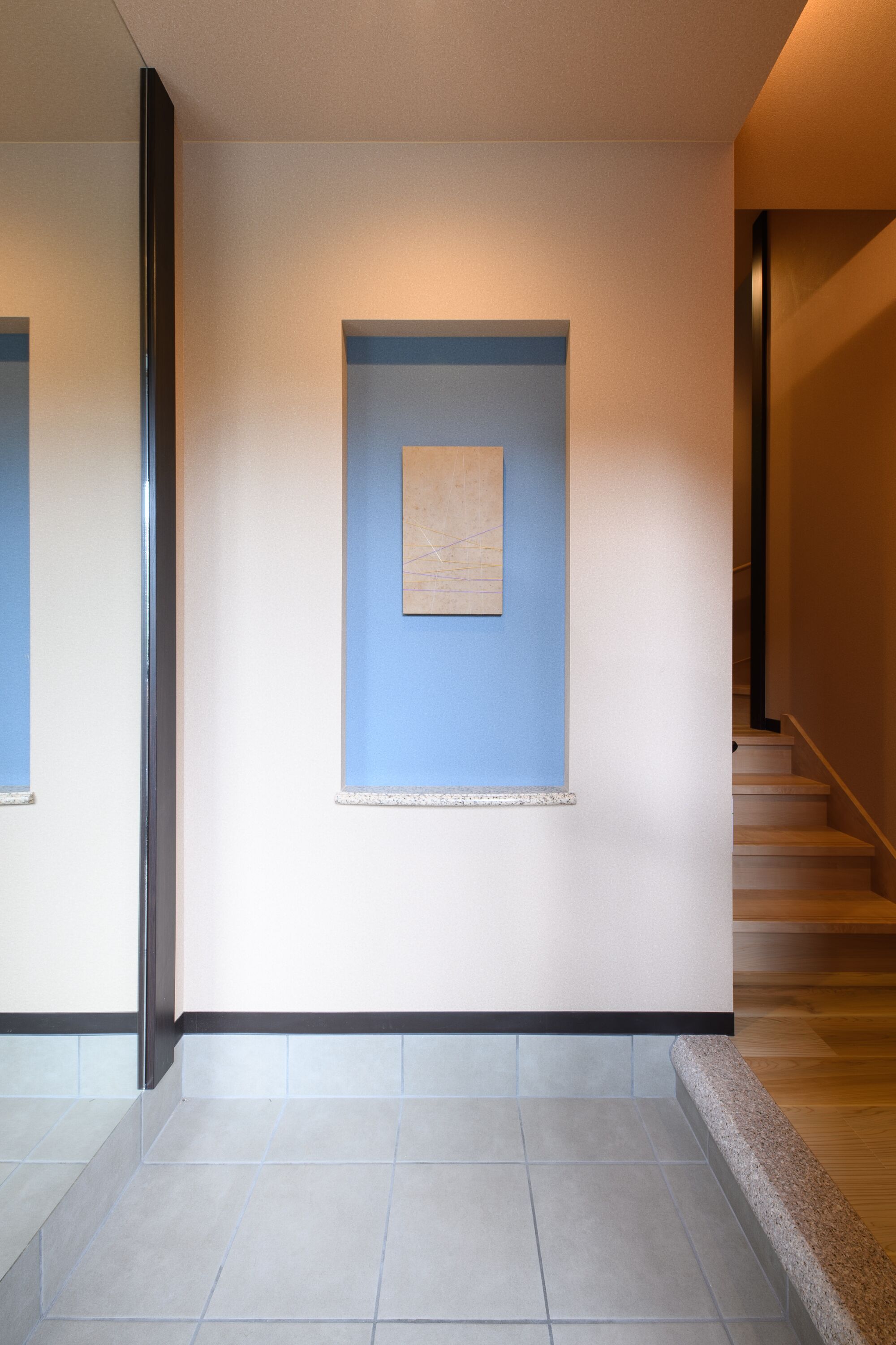 Un pasillo con una pared azul decorativa, una obra de arte enmarcada y una escalera.