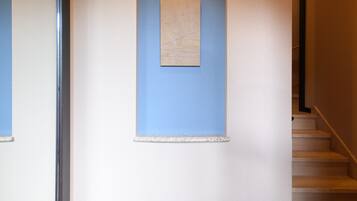 Un pasillo con una pared azul decorativa, una obra de arte enmarcada y una escalera.