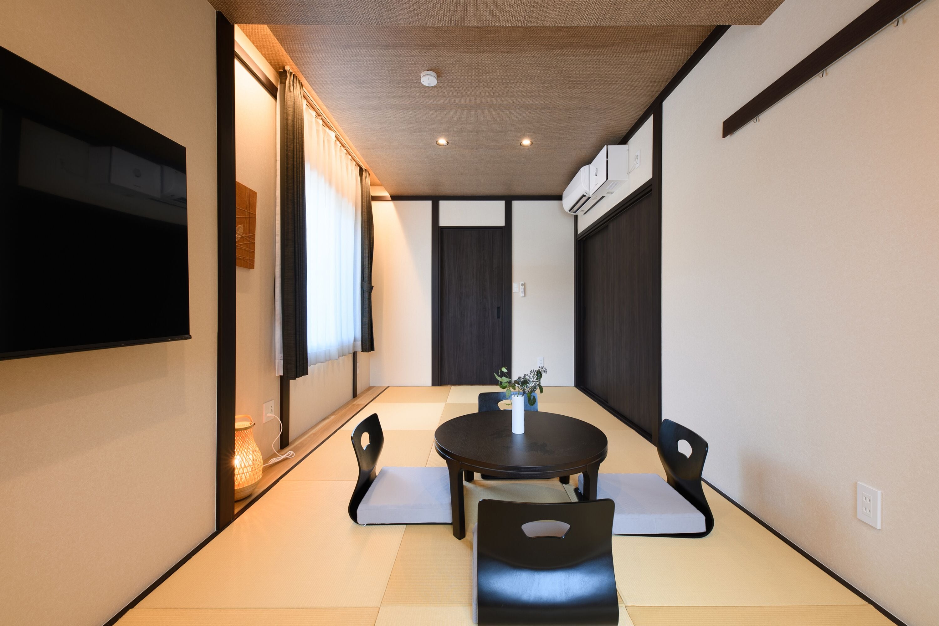 A modern dining area with a round table, black chairs, and a small plant centerpiece.