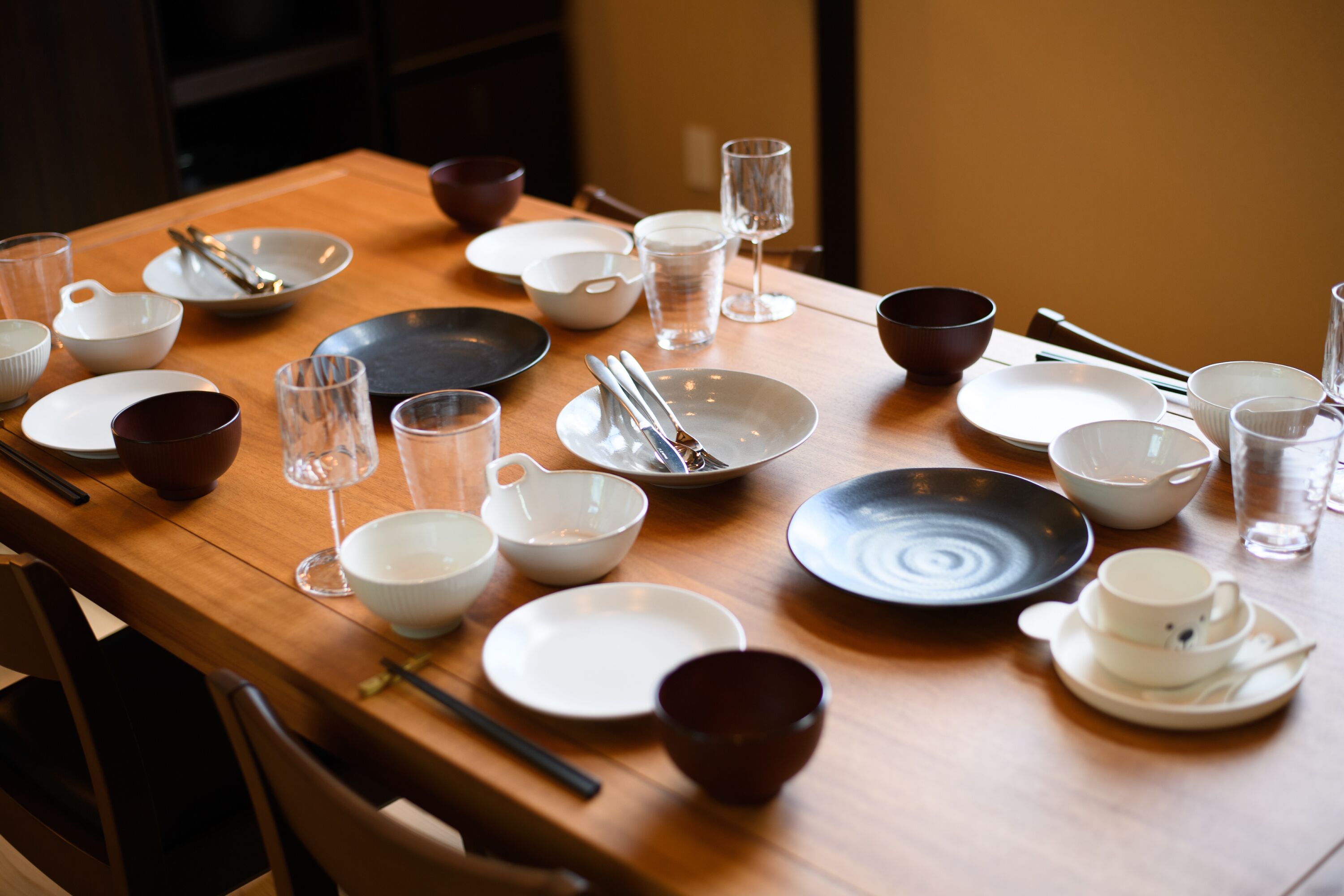 A dining table set with various bowls, plates, and glasses, arranged neatly.