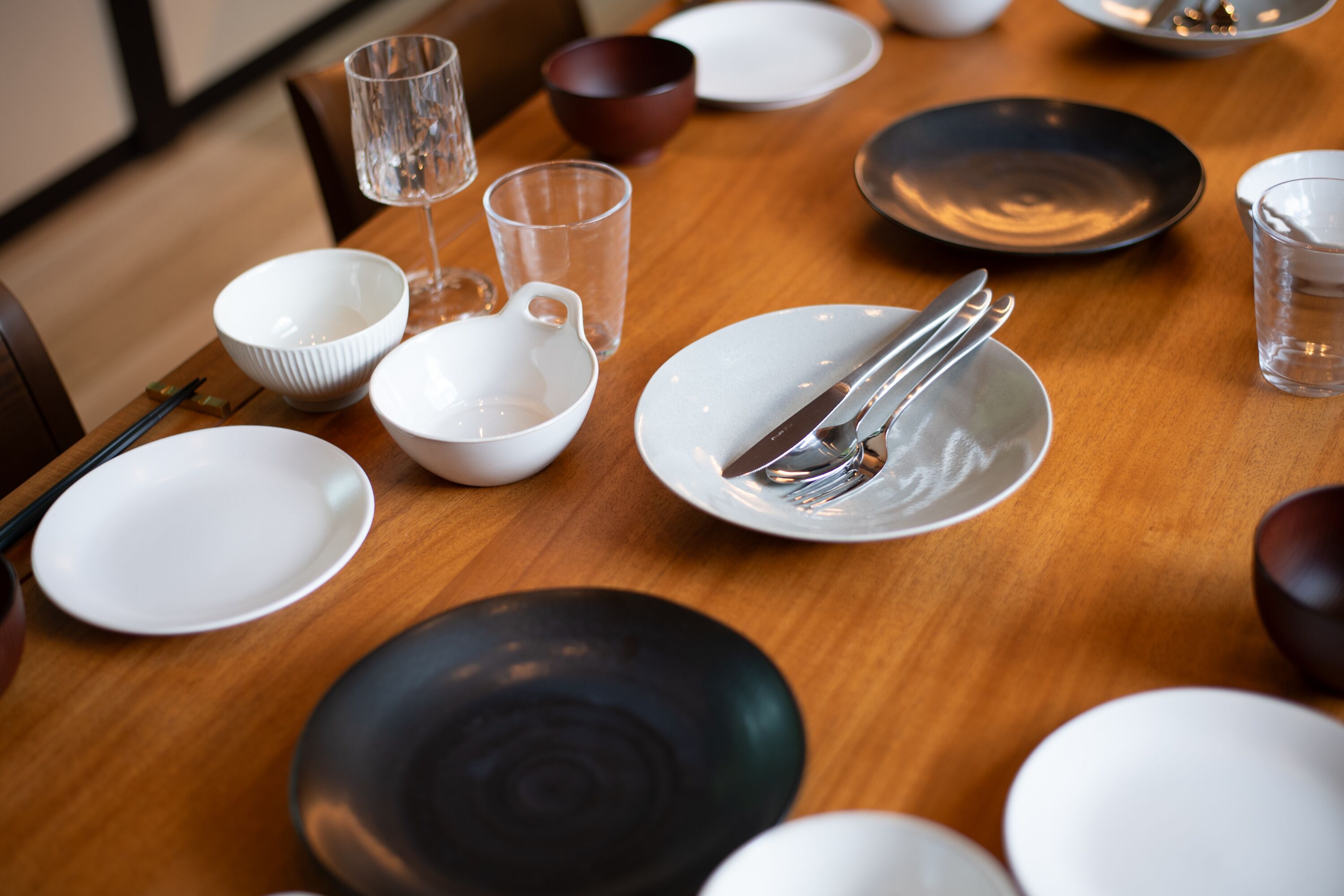A dining table with various bowls, glasses, and cutlery.