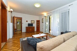A living room with a sofa, a coffee table, a television, and a cabinet. - Holiday apartment with air conditioning (Medulin)