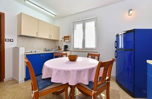 A kitchen with a round table, chairs, a blue refrigerator, and cabinets. - Holiday apartment with air conditioning (Medulin)