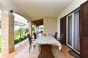 Eine überdachte Terrasse mit Tisch, Stühlen und einer Ziegelwand.