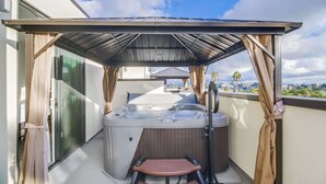 A hot tub with a pergola roof, a seating area, and a view of the city. - Park Blvd 302 | Newly Built | Spa | Central (San Diego)
