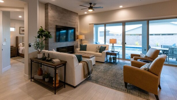 A modern living room with a fireplace, comfortable seating, a flat-screen TV, and large windows offering a view of the outdoors. - Lazy Boy Manor BL991940 by J and Amy (Mesquite)