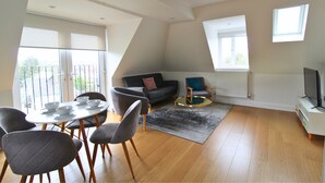 A modern living room with a dining area, a sofa, a coffee table, and a TV stand. - West Finchley by Viridian Apartments (London)