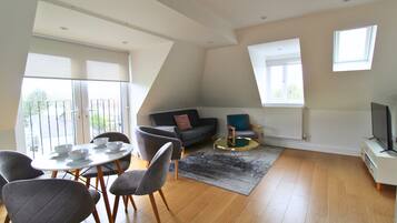 A modern living room with a dining area, a sofa, a coffee table, and a TV stand.