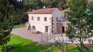 Une maison à deux étages avec une façade en pierre, un toit en tuiles et une allée gravillonnée.