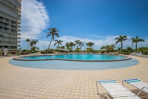 A pool area with a circular pool, palm trees, and lounge chairs.