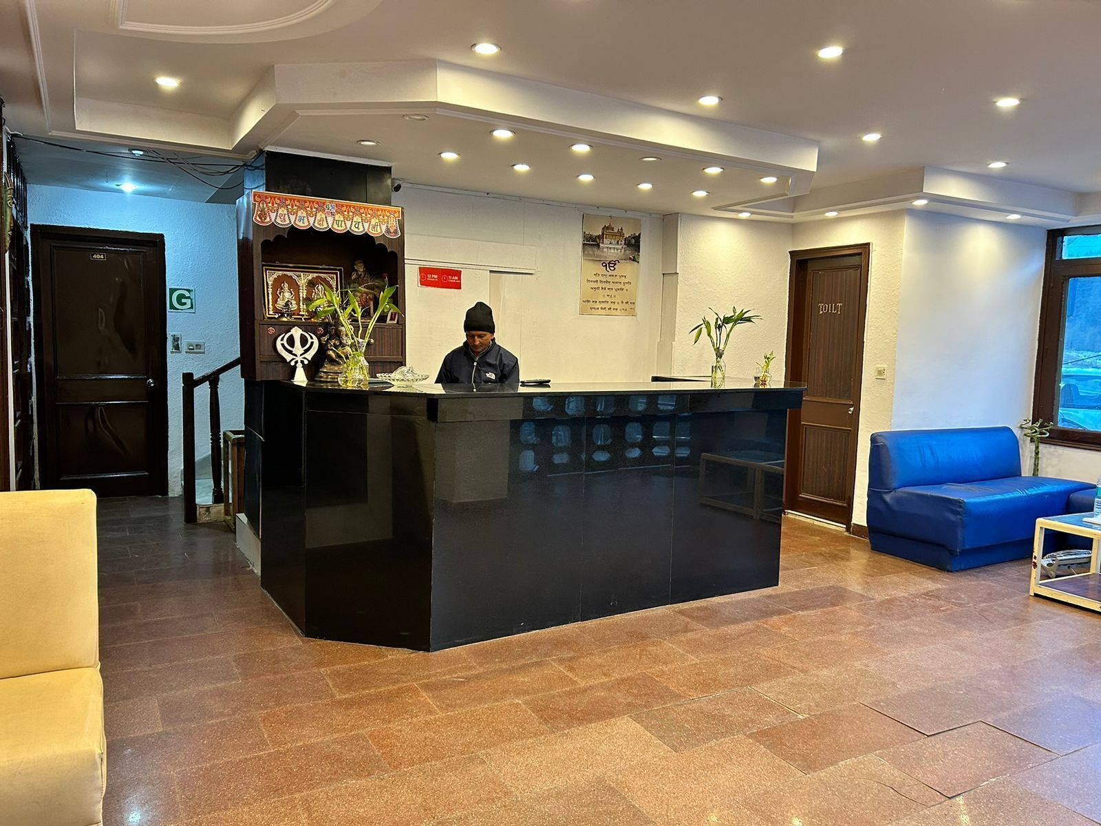 A reception area with a black counter, a blue sofa, and a wooden door labeled "TILT".