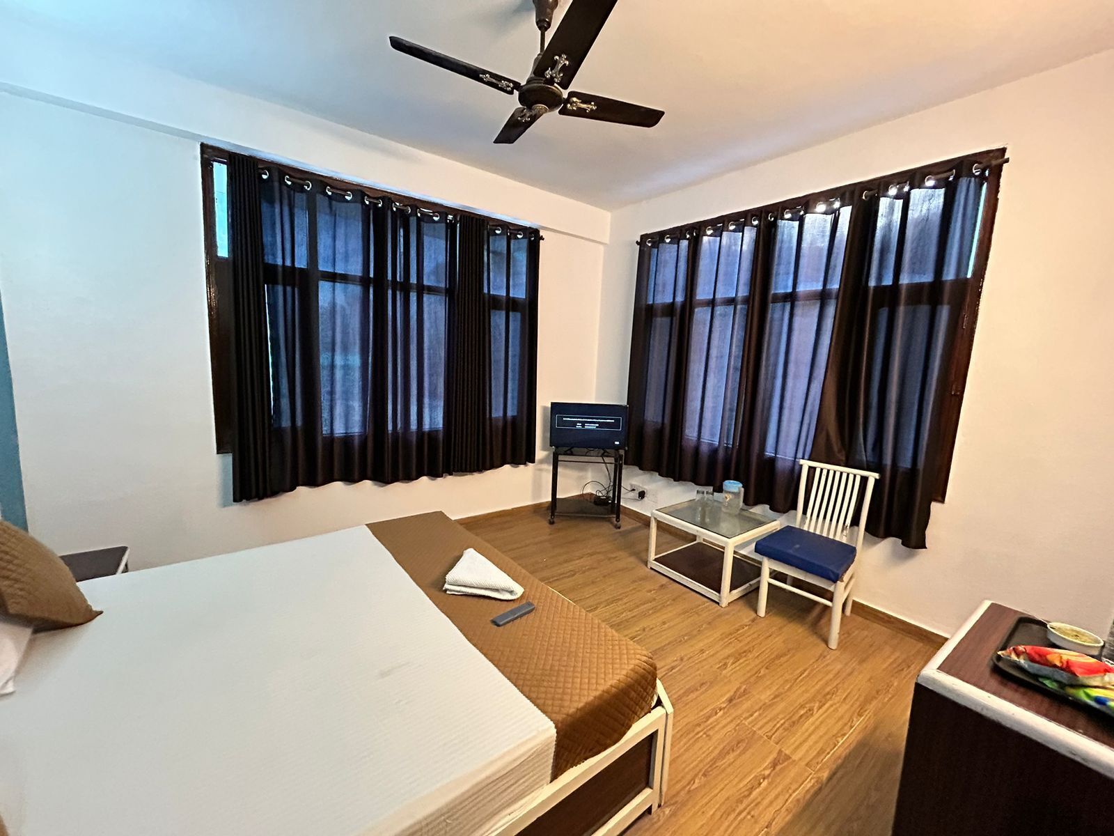 A small, clean room with a bed, a desk, a chair, and a ceiling fan.