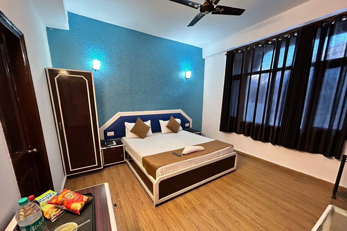 A hotel room with a bed, bedside tables, a ceiling fan, a window with curtains, and a wall with a textured finish.