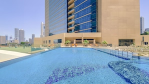 A modern hotel with a rooftop pool, a covered outdoor area with seating, and a city skyline in the background. - WelHome - Greenery Beautiful Apartment Onyx Tower 2 (Dubai)