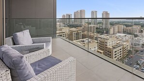 A balcony with a city view, a sofa with cushions, and a glass railing. - WelHome - Greenery Beautiful Apartment Onyx Tower 2 (Dubai)